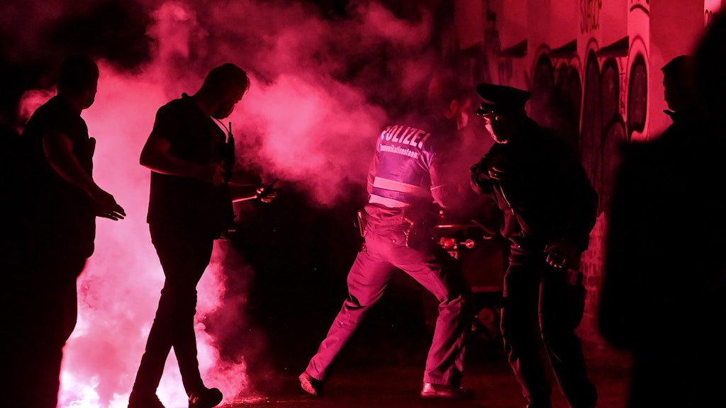 Polizeibeamte fliehen vor Pyrotechnik.