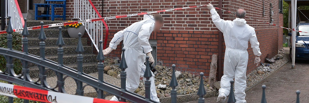 Kriminalbeamte in weißen Overalls untersuchen den Tatort. 
