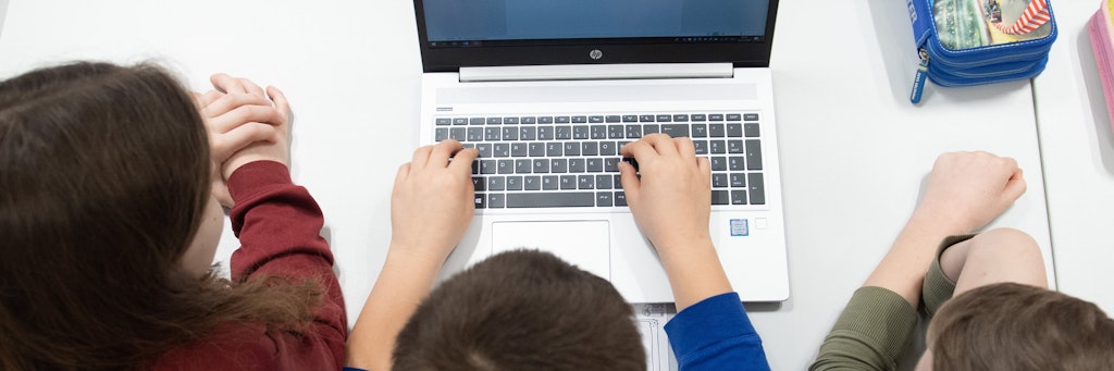 Schüler einer 3. Klasse sitzen vor einem Laptop.