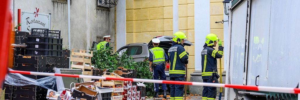 Polizisten und Feuerwehrleute arbeiten an dem abgesperrten Unfallort in St. Florian, nachdem dort ein 87 Jahre alter Autofahrer in einen Marktstand gefahren ist.