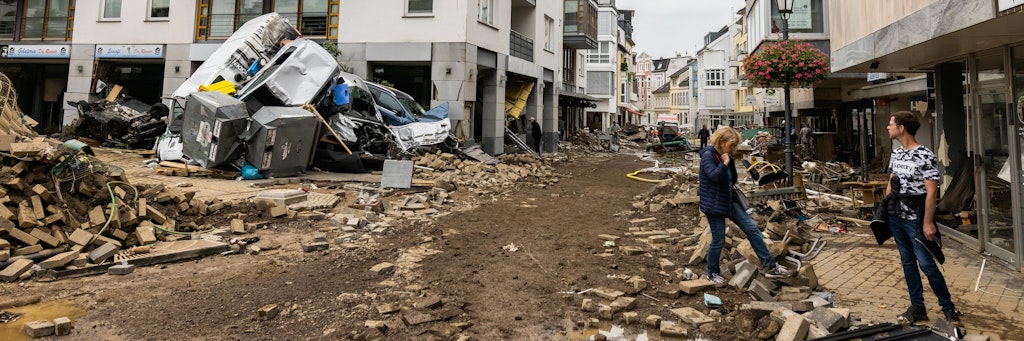 Ein Stapel Autos sowie ein Müllcontainer liegen in Bad Neuenahr auf einem vom Hochwasser völlig zerstörten Platz.