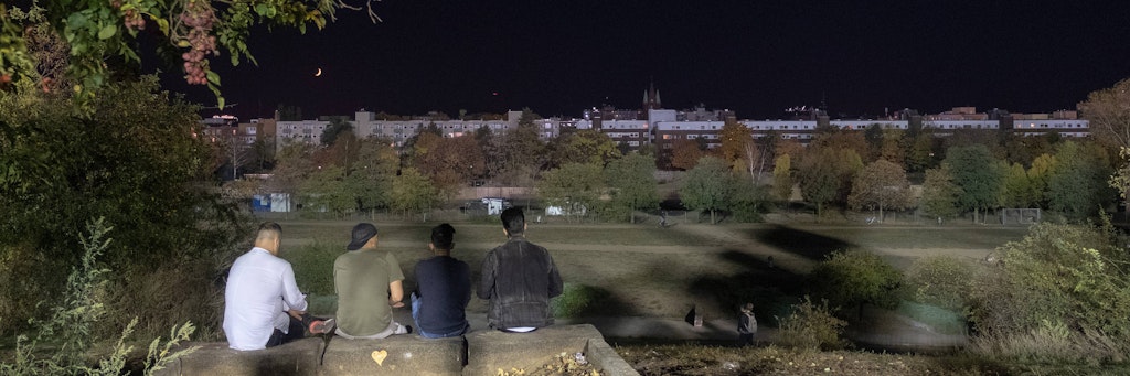 Menschen sitzen in der Nacht im Mauerpark.