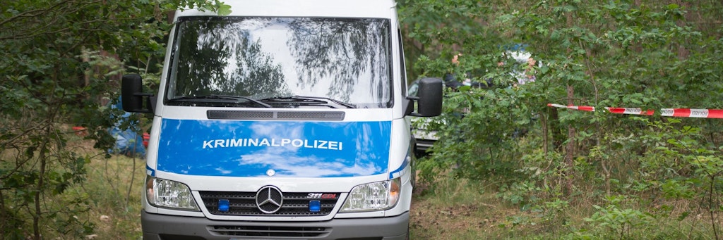 Ein Wagen der Kriminalpolizei steht in einem Wald nahe des Tatorts.