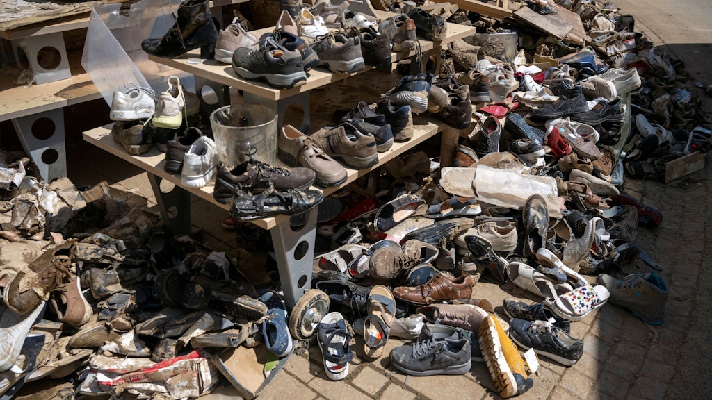 Vor einem Schuhgeschäft gestapelte, ruinierte Schuhe. 