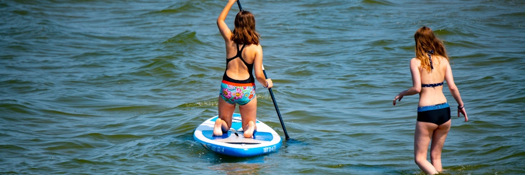 Zwei Frauen sind mit einem Stand-Up-Paddleboard auf der Ostsee unterwegs. Dort wird vor Vibrionen gewarnt.