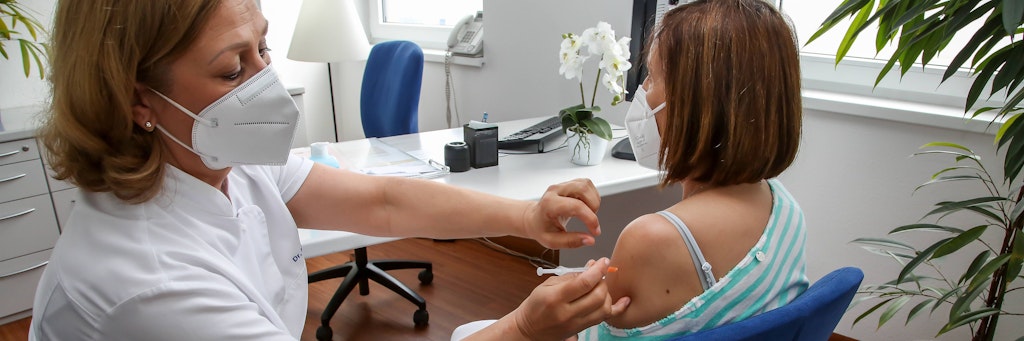 Eine Ärztin impft eine Patientin gegen Corona.