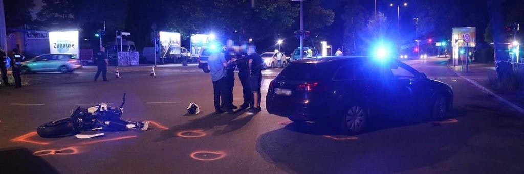 Das gerammte Motorrad, der Unfallwagen und Polizisten am Unfallort in Berlin-Marienfelde.