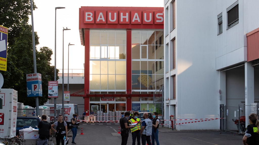 Polizisten stehen hinter Absperrbändern auf dem Gelände eines Baumarktes in Wedding. Auf dem Parkplatz sind am späten Freitagnachmittag mehrere Schüsse gefallen.