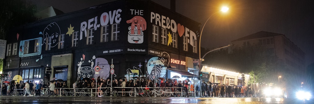 Menschen stehen im strömenden Regen dicht an dicht am Eingang zum Kitkat-Club Schlange.