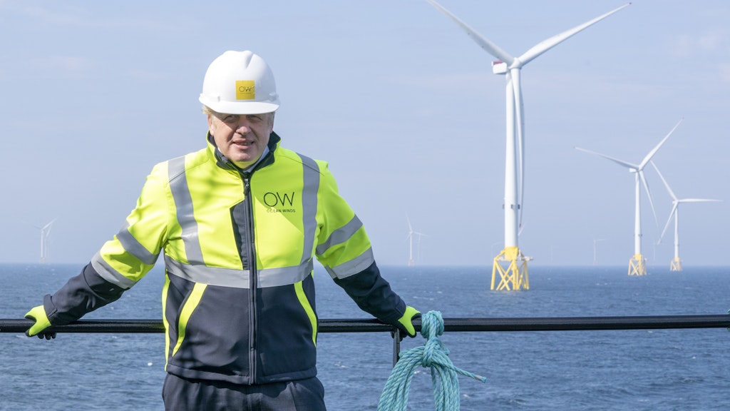 Boris Johnson, Premierminister von Großbritannien, trägt Schutzkleidung und einen Helm, als er am Deck des Schiffes „Esvagt Alba“ am Geländer steht und die Windparkanlange „Moray Offshore Windfarm East“, die im Hintergrund zu sehen ist, vor der Küste von Aberdeenshire besucht.