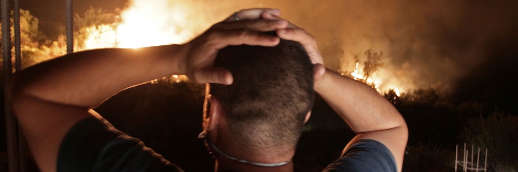 Ein Mann schlägt die Hände über dem Kopf zusammen, während er auf die Flammen eines Waldbrandes in der Nähe des algerischen Dorfes Larbaa Nath Irathen starrt.