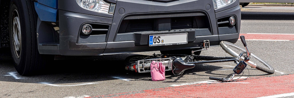 Ein Fahrrad liegt nach einem Unfall auf einer Straße mit einem Radweg unter einem LKW (Symbolbild).