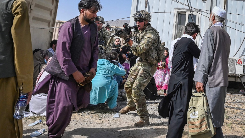 Ein US-Soldat herrscht auf dem Flughafen Kabul mit erhobener Waffe einen Afghanen an.