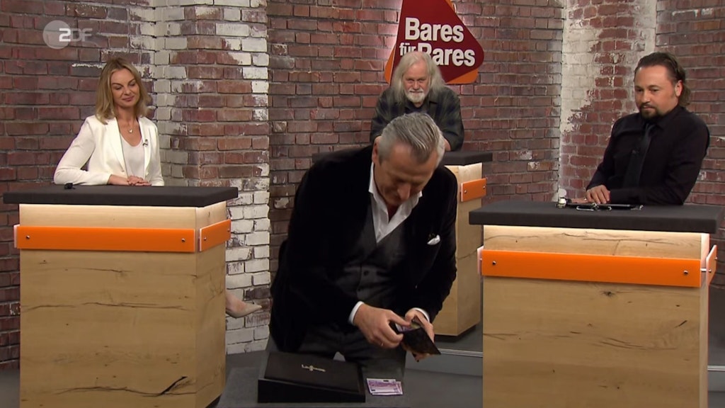 „Bares für Rares“-Händler Markus Wildhagen gibt das Höchstgebot für den Kreuzanhänger ab.