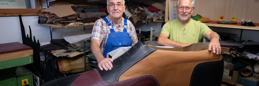 Die Schuhmachermeister Matthäus Jörg (l.) und Johannes Schunk (beide 72) in Jörgs Werkstatt hinter dem überdimensionierten Schuh in Größe 240.