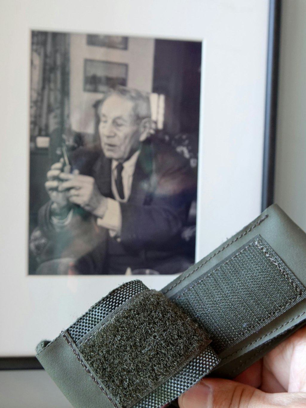 Ein Etui mit Klettverschluss für ein Schweizer Taschenmesser. Im Hintergrund ein Bild von George de Mestral. Der Schweizer hatte das Patent auf den Klettverschluss 1951 angemeldet. 