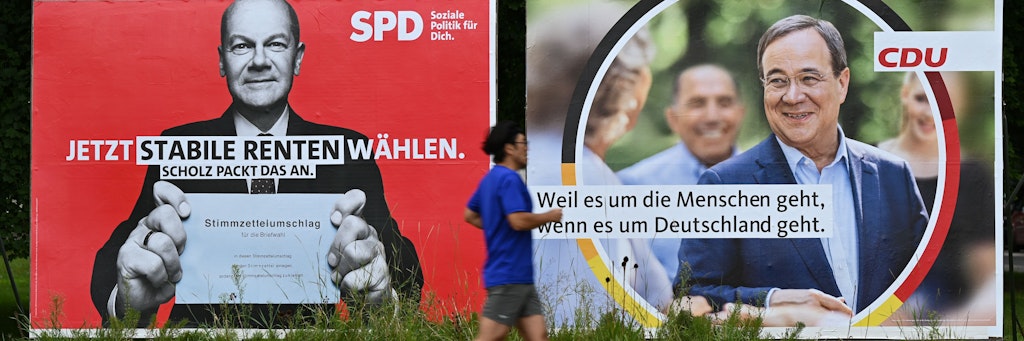 Ein Mann joggt an Wahlplakaten der SPD mit Olaf Scholz (l.) und der CDU mit Armin Laschet vorbei. 