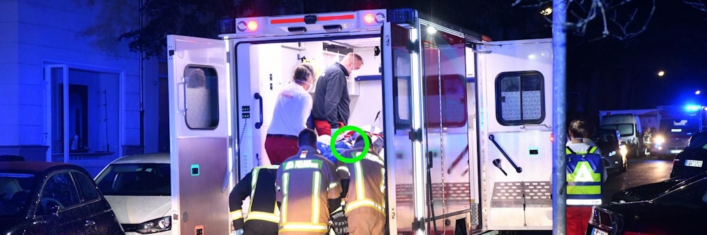 Das Messer steckt noch in der Brust der Frau, als die Feuerwehr sie in den Rettungswagen schiebt. 