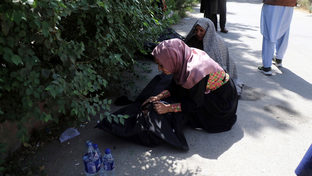 Leichen sind auf einem Weg an einem Krankenhaus in Kabul abgelegt. Frauen versuchen festzustellen, ob es vermisste Angehörige sind.