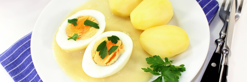Zu Süßsauren Eiern gehören traditionell Salzkartoffeln, gut schmecken sie aber auch mit Kartoffelbrei. 
