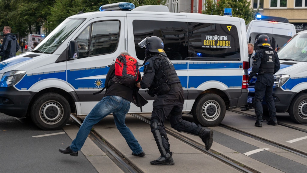 Ein Polizist hält einen Teilnehmer einer Demonstration fest.