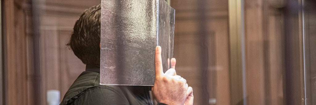 Der Angeklagte Muhamed R. (31) steht in einer Kabine aus Panzerglas vor Gericht.