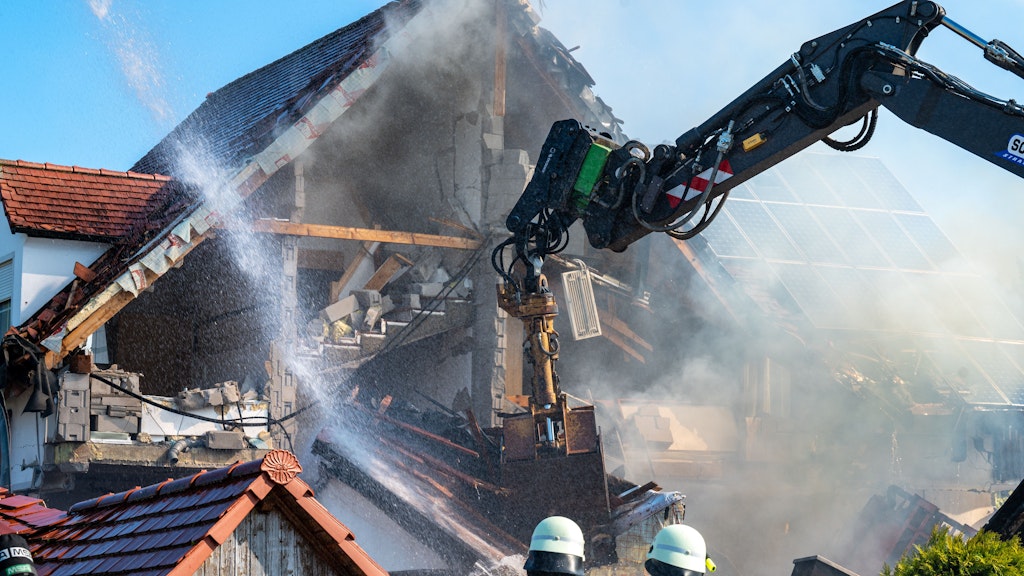 Ein Bagger räumt Teile des eingestürzten Hauses ab und Einsatzkräfte der Feuerwehr sind in der Nähe eines Hauses im Einsatz, in dem es zuvor nach Angaben der Polizei eine Explosion gegeben hatte.
