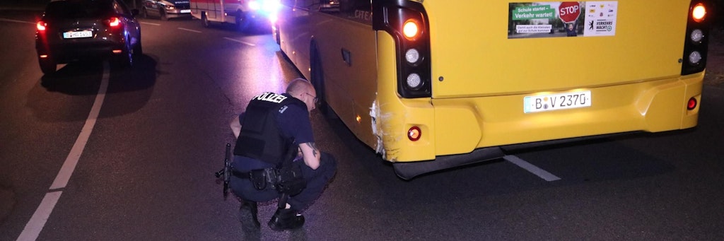 Ein Polizist nimmt den Schaden am BVG-Bus unter die Lupe.