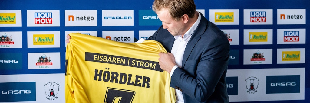 Eisbären-Kapitän Frank Hördler wurde vom Hauptsponsor mit einem goldenen Winner-Trikot überrascht, das ihm sichtlich gefällt. 