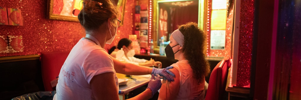 Impfaktion auf der Hamburger Reeperbahn: Eine junge Frau lässt sich im Rahmen der Aktion „Kiez-Piks“ in einer Bar impfen. Solche originelle Maßnahmen sollen bislang Unentschlossene zum Pieks bewegen. Doch reicht das?