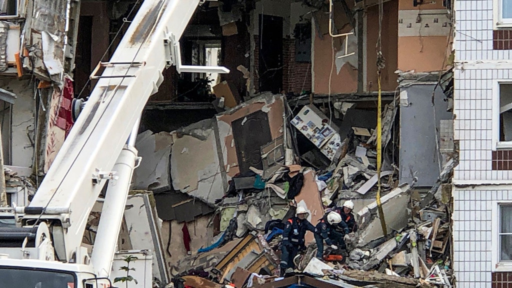 Russische Rettungskräfte arbeiten am Ort einer Gasexplosion in einem neunstöckigen Wohnhaus, mit Toten und Verletzten.