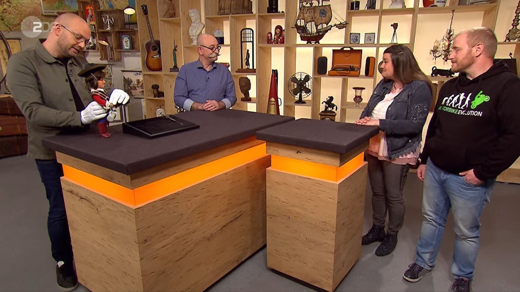 „Bares für Rares“-Horst Licher mit seinem Experten Sven Deutschmanek, der Musketier-Puppe und den Kandidaten Elke und Lutz Klästers.