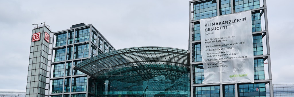 „Klimakanzler:in gesucht!“ steht auf einem großen Transparent von Greenpeace am Berliner Hauptbahnhof hängt.