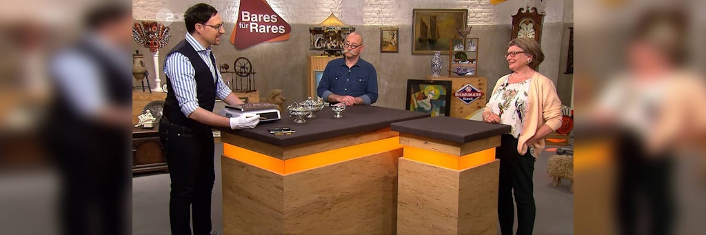 Colmar Schulte-Goltz schätzt bei „Bares für Rares“ ein Teeservice für Moderator Host Lichter und Kandidatin Christine Steiner ein.