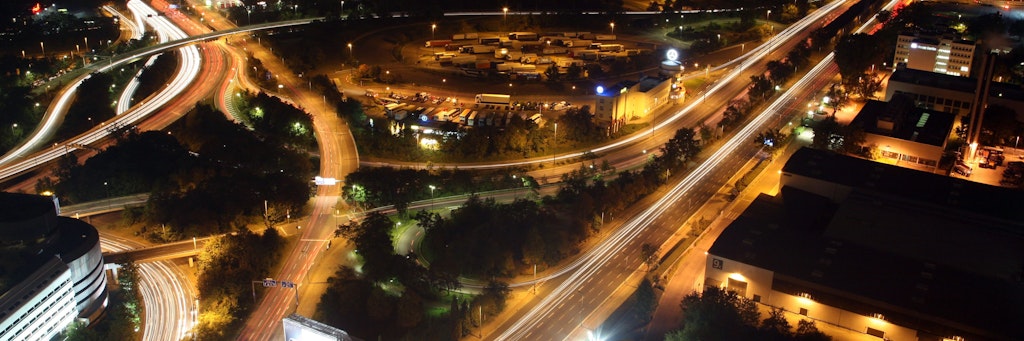 Zahlreiche Fahrzeuge bewegen sich Abend im Feierabendverkehr über das Autobahndreieck Funkturm in Berlin; links verschwindet die A100 und rechts die Avus in Richtung Potsdam.