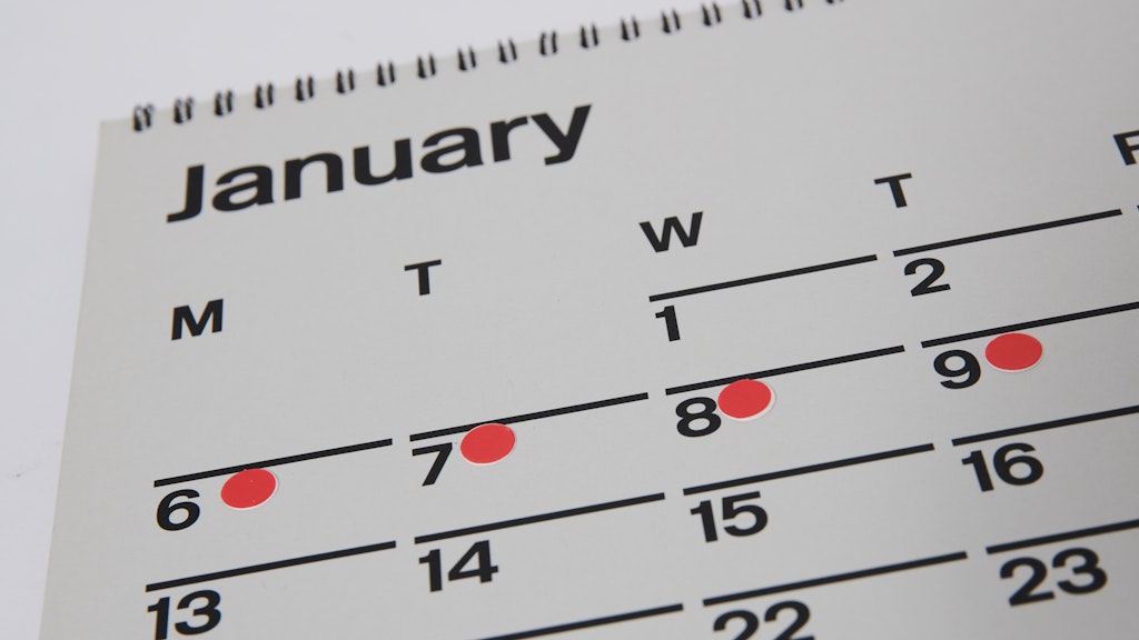 Rote Punkte markieren den Zyklus einer Frau auf einem Kalender. Einige Frauen berichten über stärkere, schwächere oder eine unregelmäßige Menstruation sowie Zwischenblutungen nach der Corona-Impfung. 