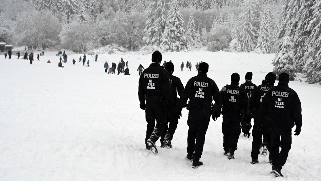 Einsatzkräfte der Polizei gehen über die Rodelpiste „Brockenblick“ am Nationalpark-Besucherzentrum Torfhaus im Harz.