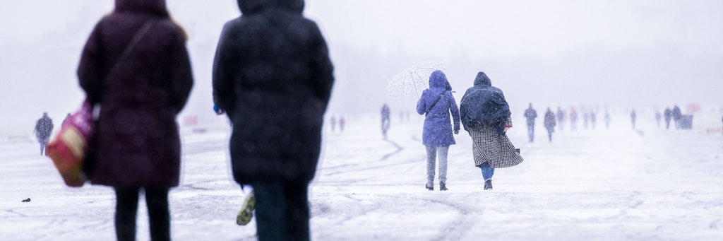 Berliner spazieren bei Schneefall über das Tempelhofer Feld.