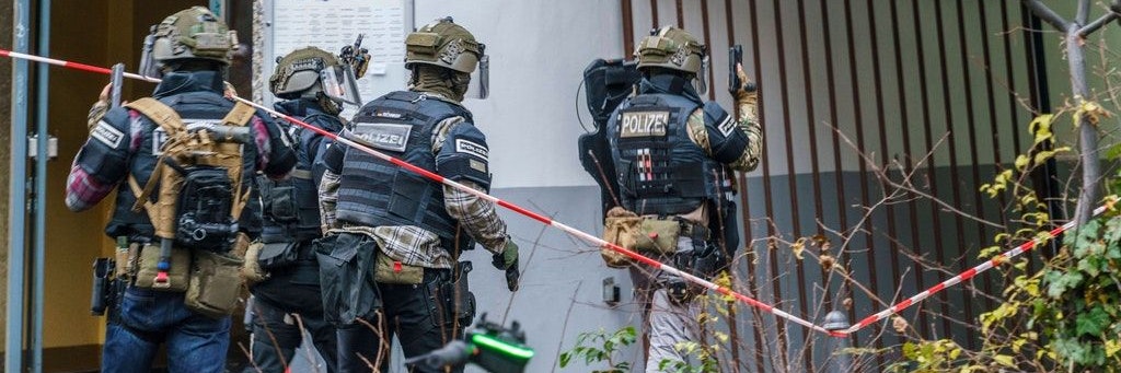 Beamte eines Spezialeinsatzkommandos betreten schwer bewaffnet ein Haus (Symbolbild).