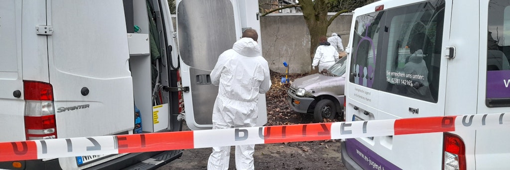 Kriminaltechniker der Polizei untersuchen den mit einem Absperrband der Polizei abgesperrten Tatort auf einem Parkplatz in Hamm.