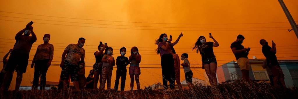 Anwohner beobachten die Rauchwolken am Himmel, die durch den Waldbrand entstanden sind. 