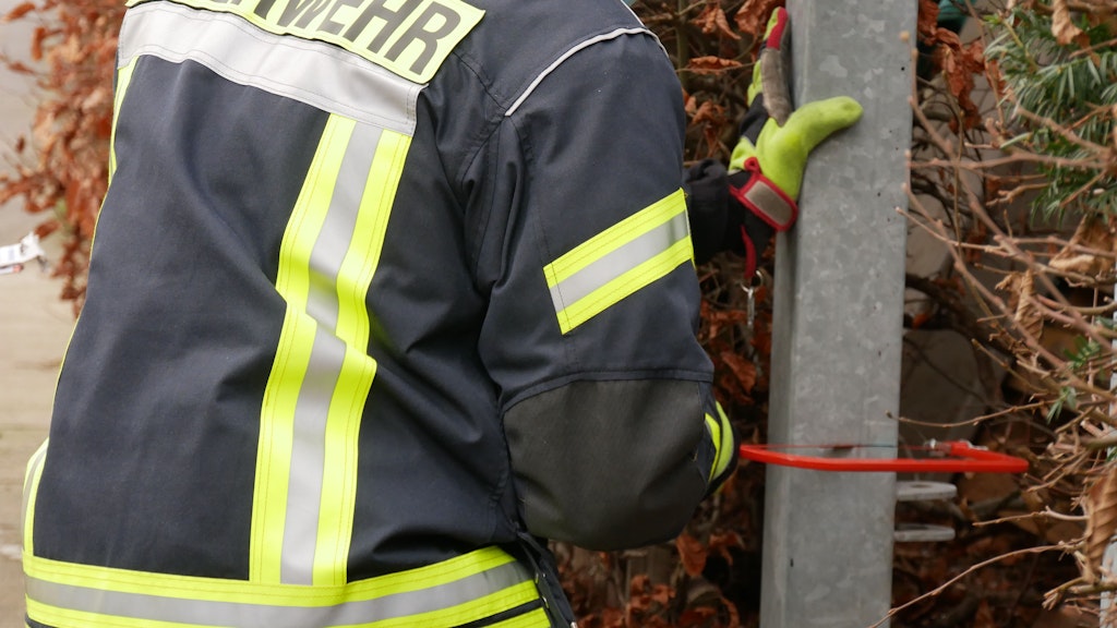 Mit einer Handsäge wird der Zaunpfahl abgesägt.