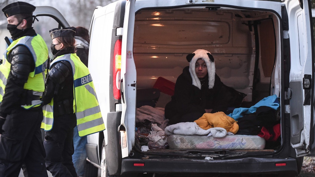 Eine Raverin mit Panda-Mütze sitzt in ihrem zum Schlafzimmer umgewidmeten Van.