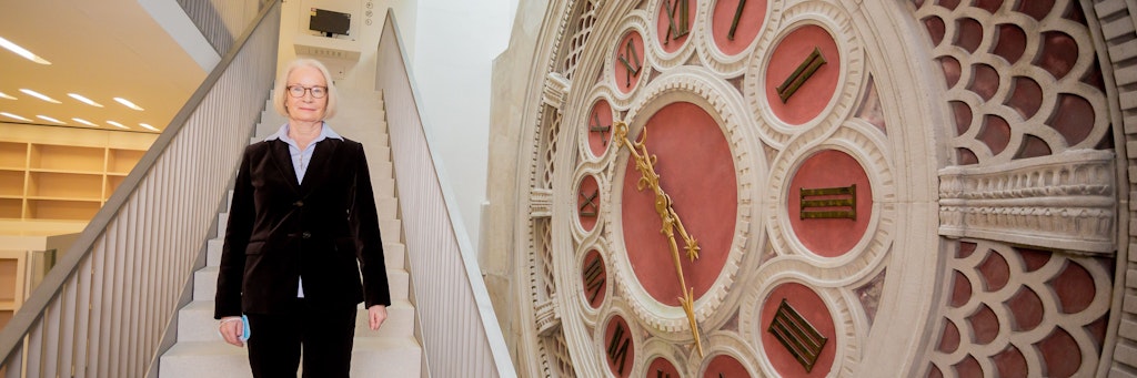 Barbara Schneider-Kempf, Generaldirektorin der Staatsbibliothek zu Berlin, steht neben der Uhr, die für immer stehen geblieben ist. Die goldfarbenen Zeiger der riesigen Lesesaaluhr stehen auf 22 Uhr 25. Um die Zeit schlug die Fliegerbombe in der Preußischen Staatsbibliothek ein, am 15. Februar des Kriegsjahres 1944. 
