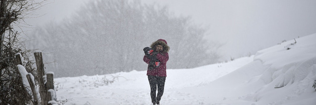 Eine Frau trägt im nordspanischen Pamplona ihr Haustier durch den Schnee.