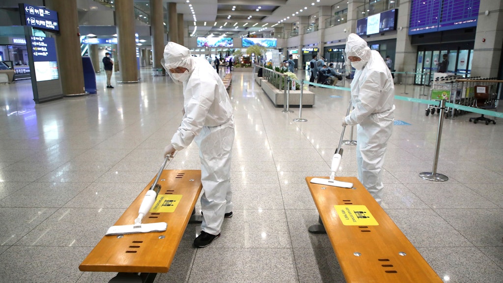 Mitarbeiter in Schutzkleidung desinfizieren in Südkorea Bänke in der Ankunftshalle des internationalen Flughafens Incheon. In Südkorea sind nun ebenfalls Fälle der in Großbritannien entdeckten Mutation des Coronavirus nachgewiesen worden. 