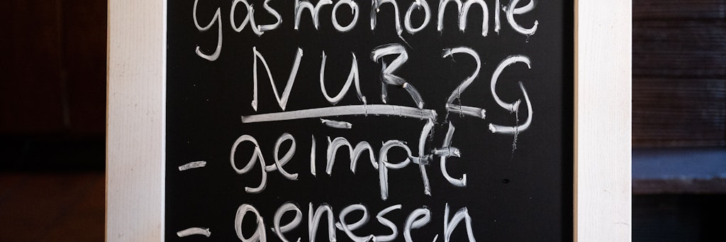 Eine Tafel mit der Aufschrift «Innengastronomie - Nur 2G - geimpft - genesen» steht in einem Lokal.
