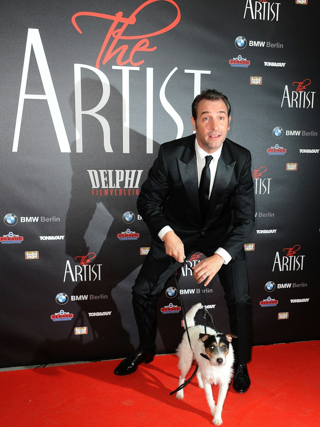 Der französische Schauspieler Jean Dujardin kommt mit dem Filmhund Uggie über den roten Teppich zur Deutschland-Premiere des Films „The Artist“.
