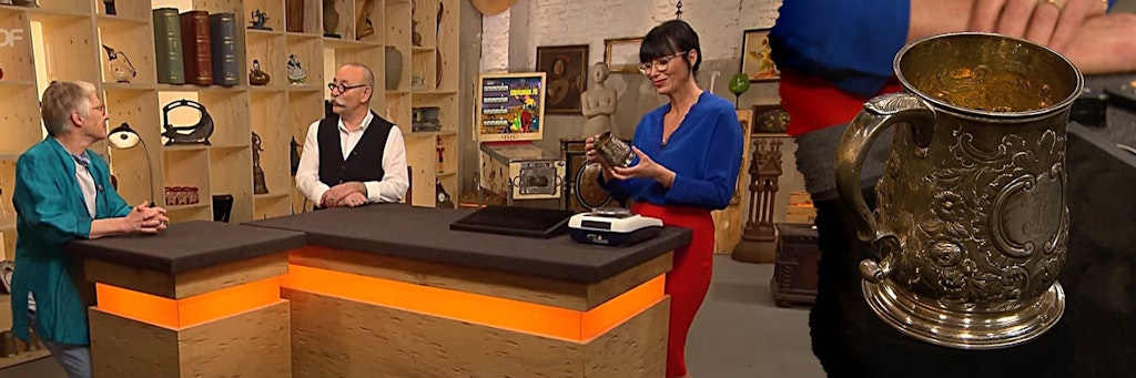 Dieser Becher kam bei „Bares für Rares“ unter den Hammer. Links: Moderator Horst Lichter, Expertin Heide Rezepa-Zabel und Kandidatin Lis Prussen bei der Expertise.
