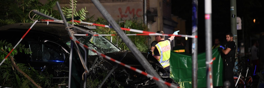 An einem zerstörten Auto halten Polizisten eine Plane. In Berlin-Mitte sind bei dem schweren Verkehrsunfall vier Menschen getötet worden. Ein Auto war an der Ecke Invalidenstraße und Ackerstraße auf einen Gehweg gefahren.